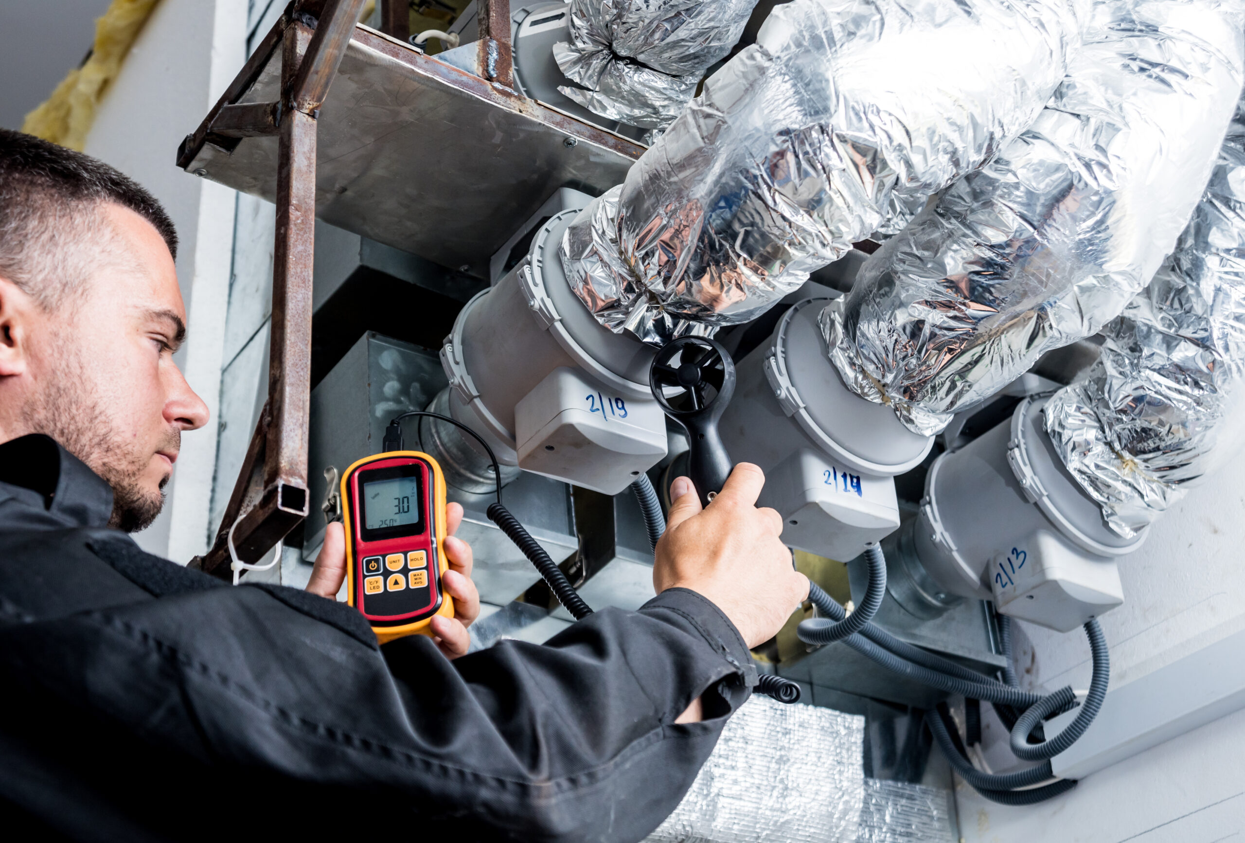 Mechanic checking car air conditioning system with gauges